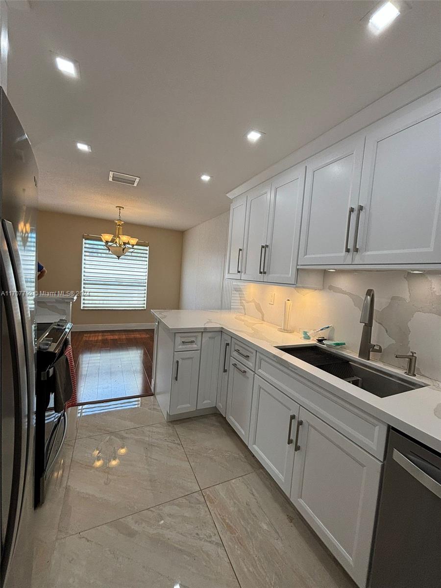 a kitchen with granite countertop a stove top oven a sink a counter space and cabinets