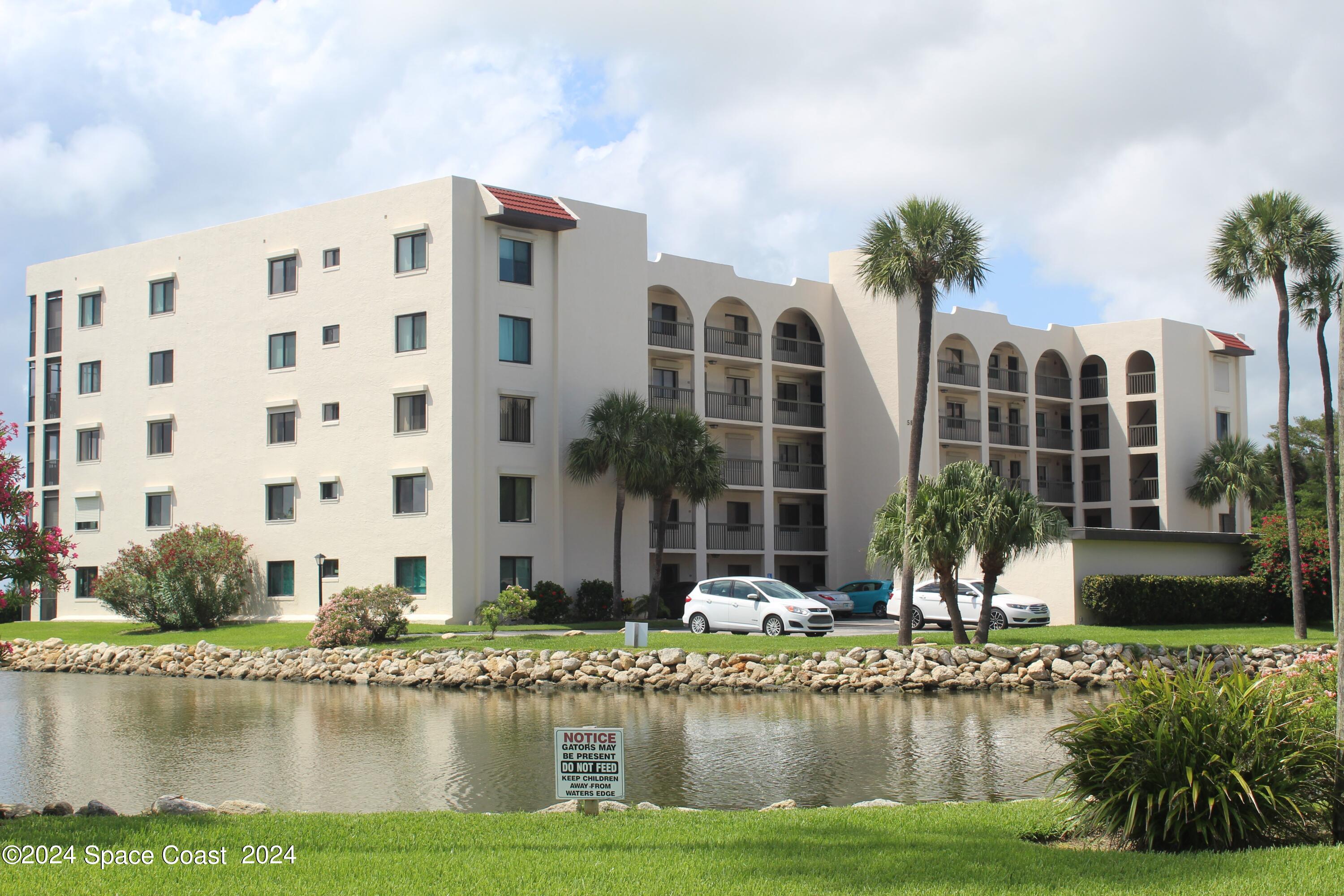 a front view of a residential apartment building with a yard and swimming pool