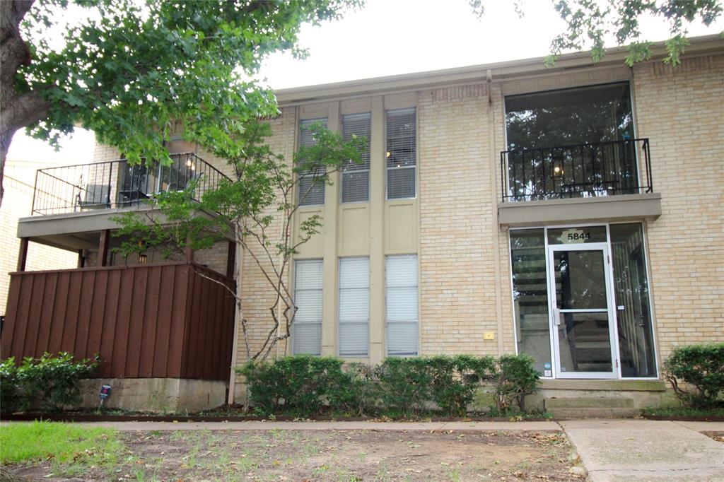 a front view of a house with a tree