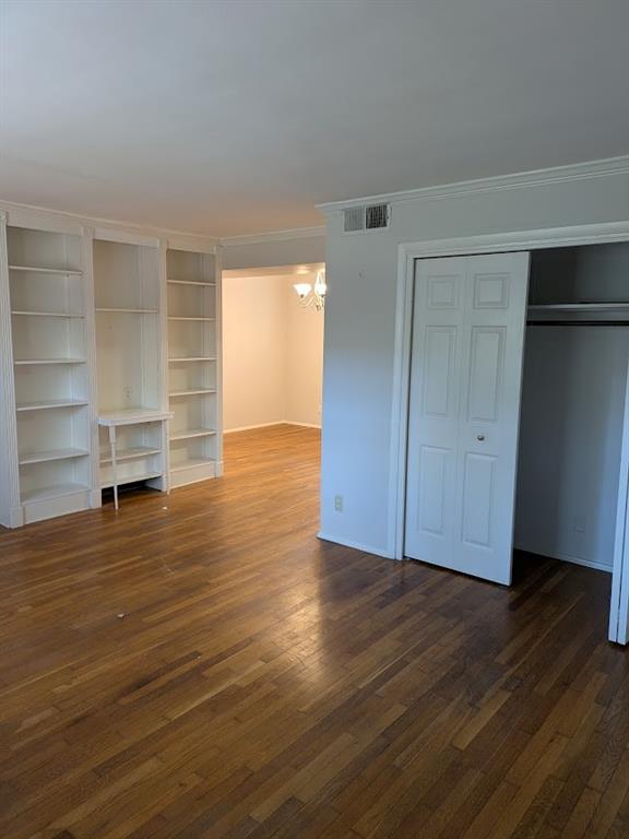 an empty room with wooden floor closet and windows