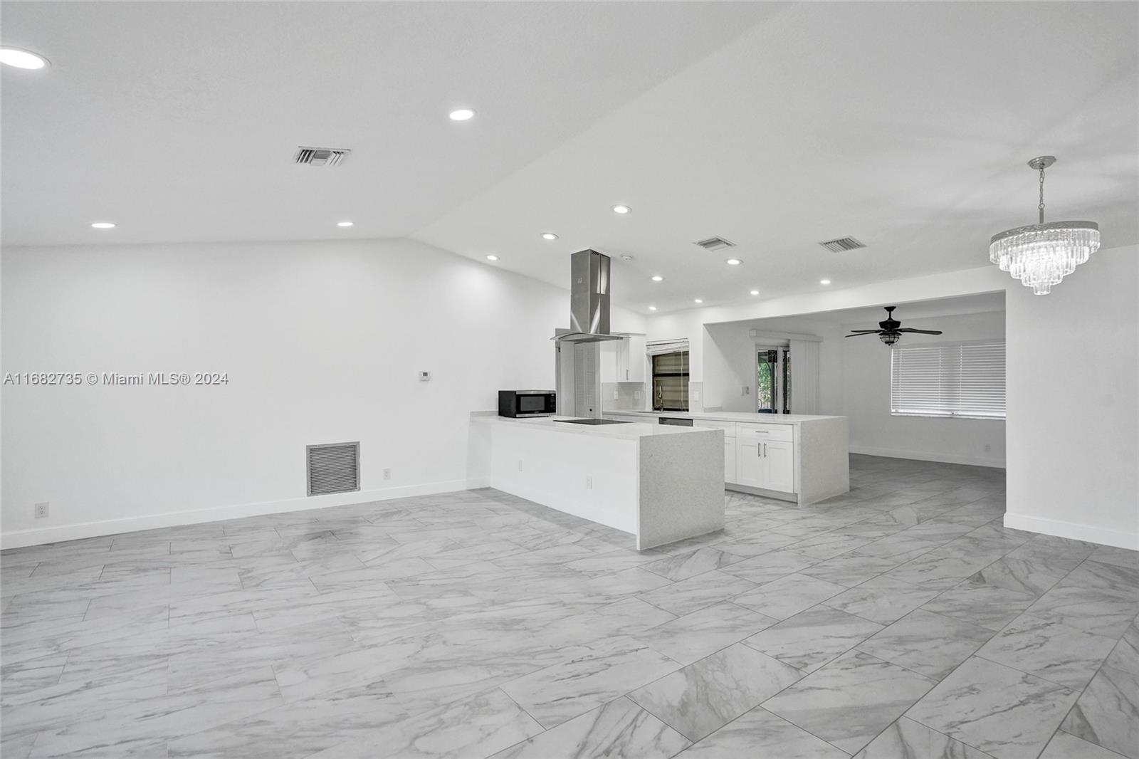 a large white kitchen with kitchen island a sink a counter and a fireplace