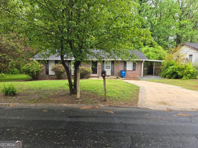 a view of house in front of a big yard with large trees