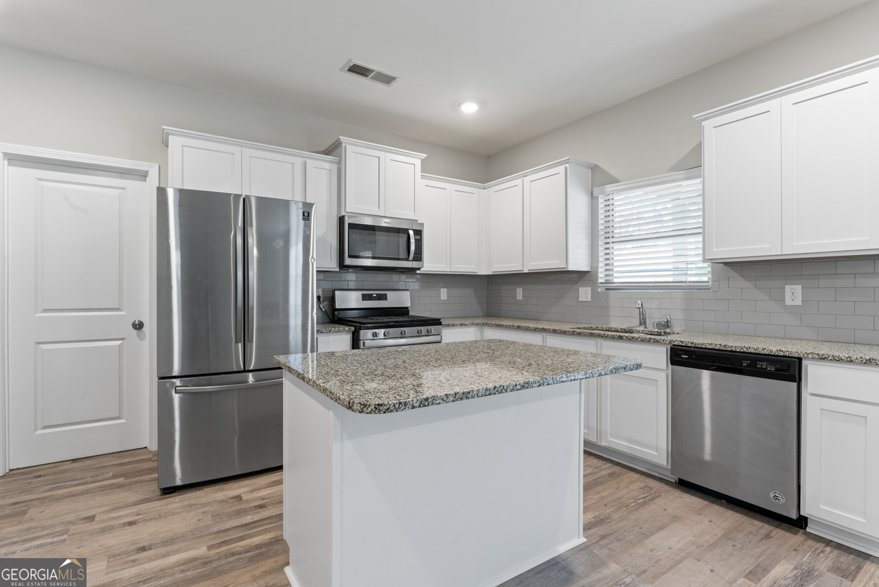 a kitchen with a refrigerator a microwave a sink and cabinets