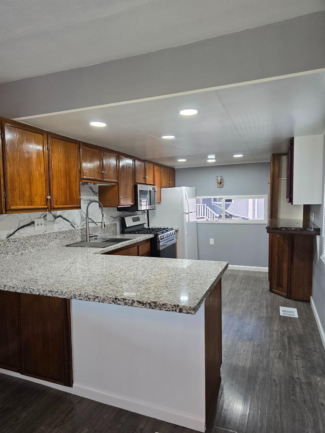 a large kitchen with a large counter top stainless steel appliances and cabinets