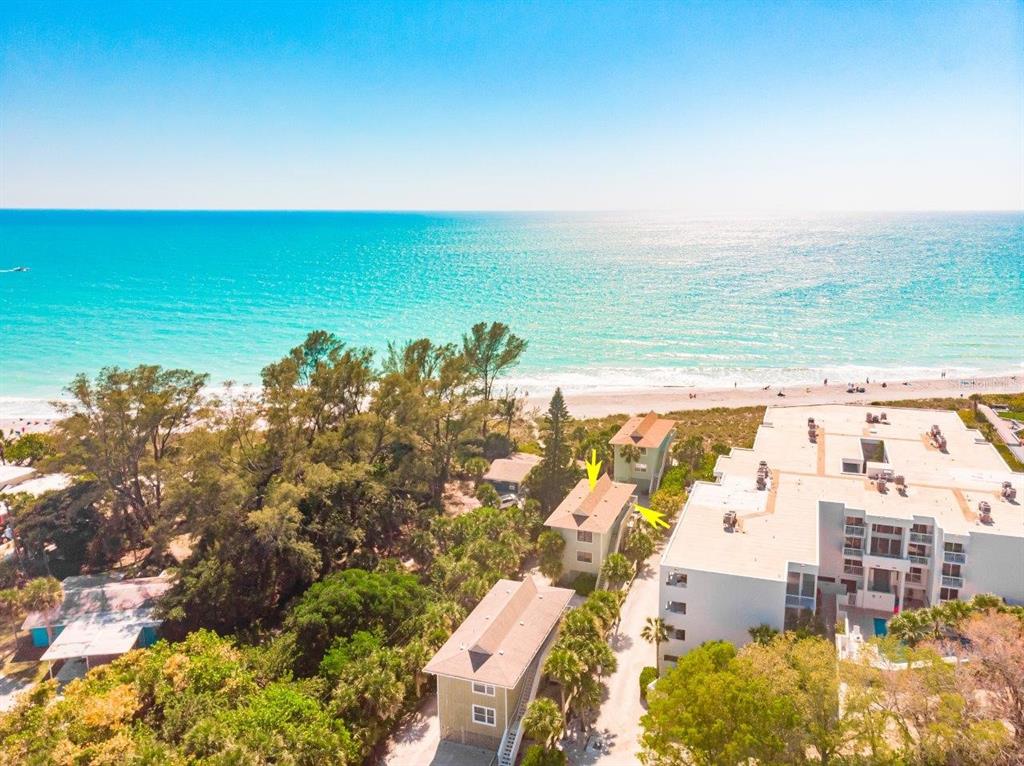 an aerial view of ocean and residential houses with outdoor space