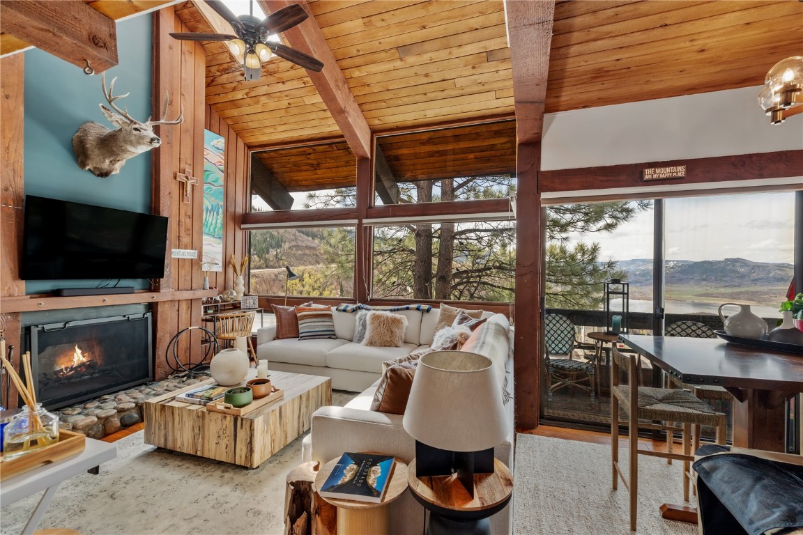 Living room featuring a mountain view, ceiling fan, hardwood / wood-style floors, vaulted ceiling with beams, and wood ceiling