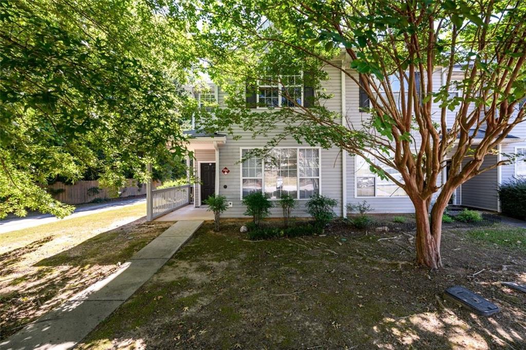 a view of a white house next to a yard with large trees