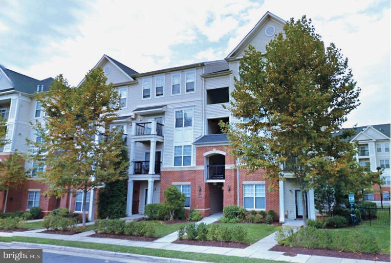 a front view of a residential apartment building with a yard and garage