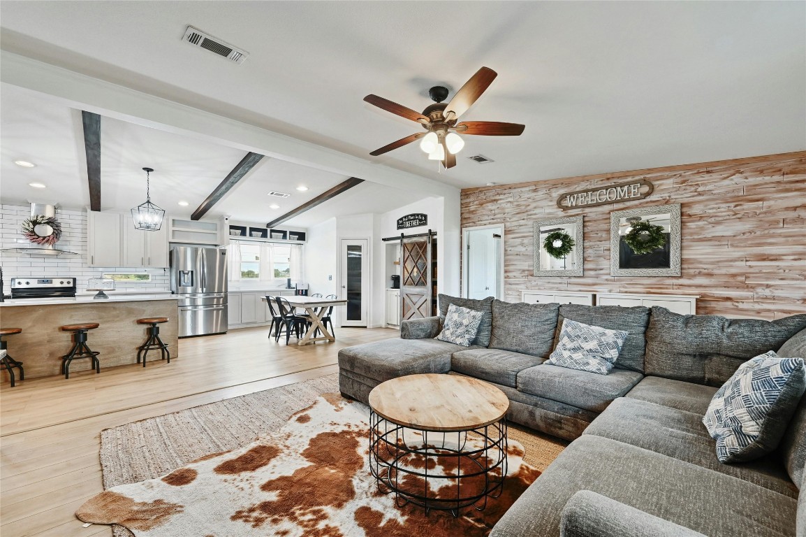 a living room with furniture kitchen view and a chandelier