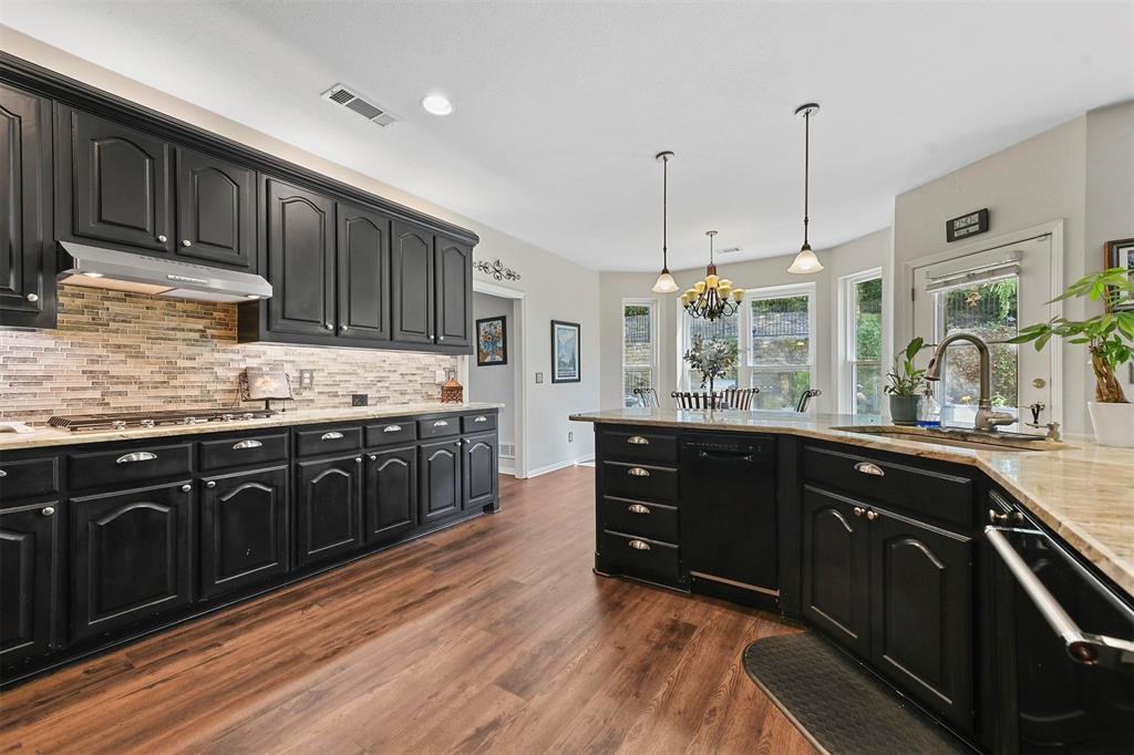 a kitchen with stainless steel appliances granite countertop a sink a stove and a wooden cabinets