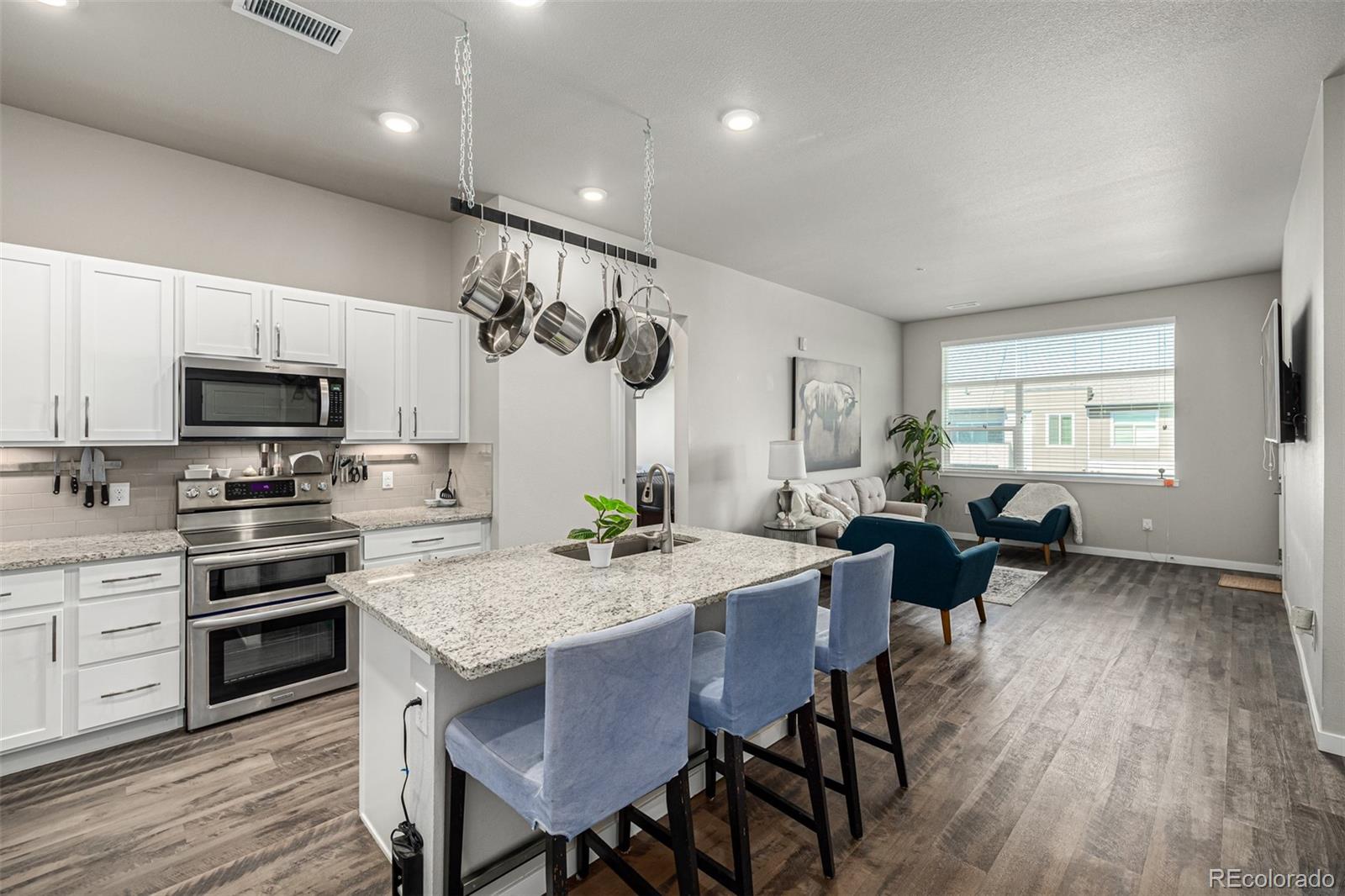 a kitchen with granite countertop a stove a sink a dining table and chairs