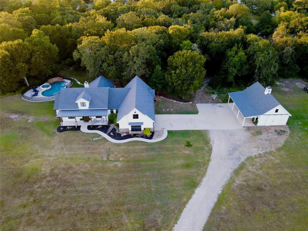 an aerial view of a house with swimming pool and large trees