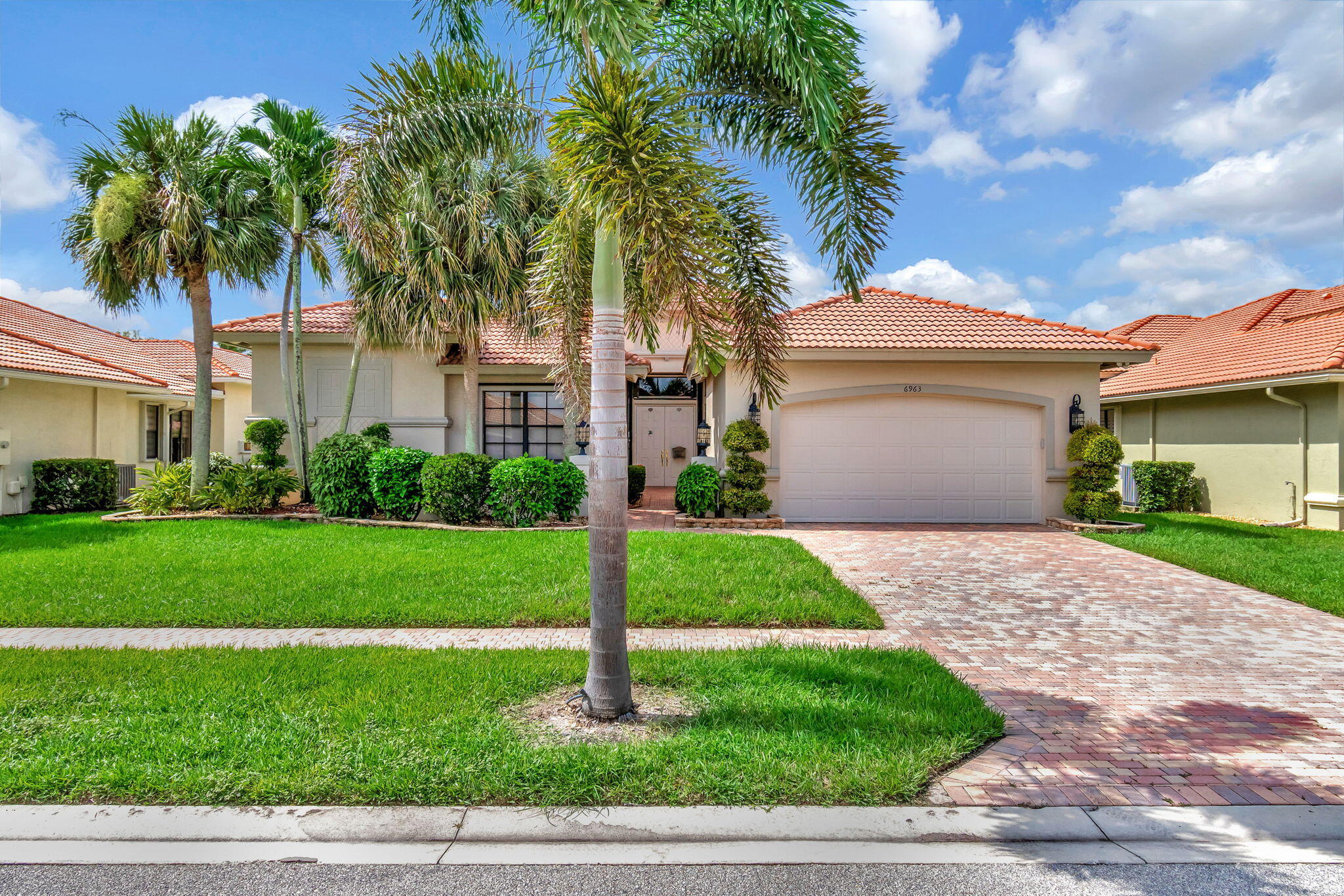 a front view of a house with a garden and palm tree