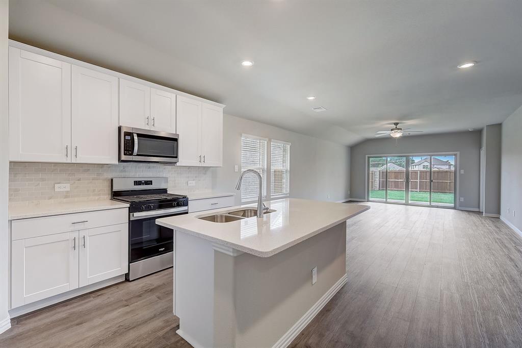 a kitchen with kitchen island granite countertop a stove sink and microwave