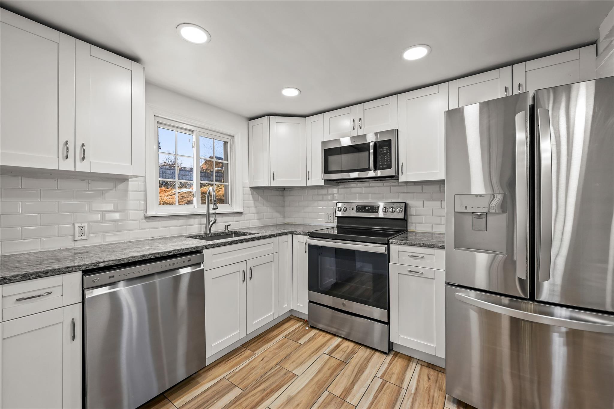 a kitchen with stainless steel appliances granite countertop a stove a sink and a refrigerator