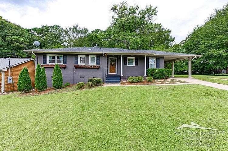 a front view of a house with a yard and green space