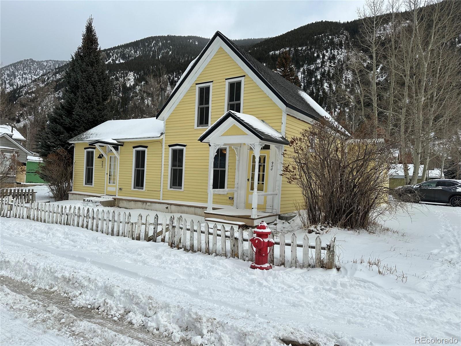 a view of a white house with a yard covered with snow in the road