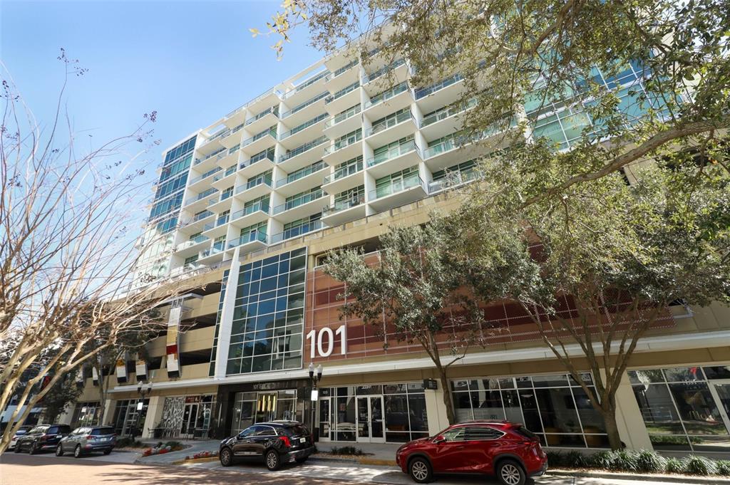 a front view of a building with lot of cars and trees