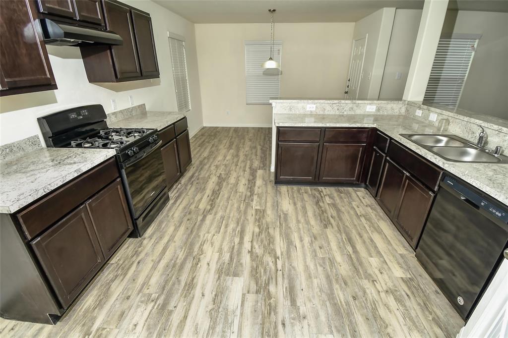 a kitchen with a sink a stove wooden floor and cabinets