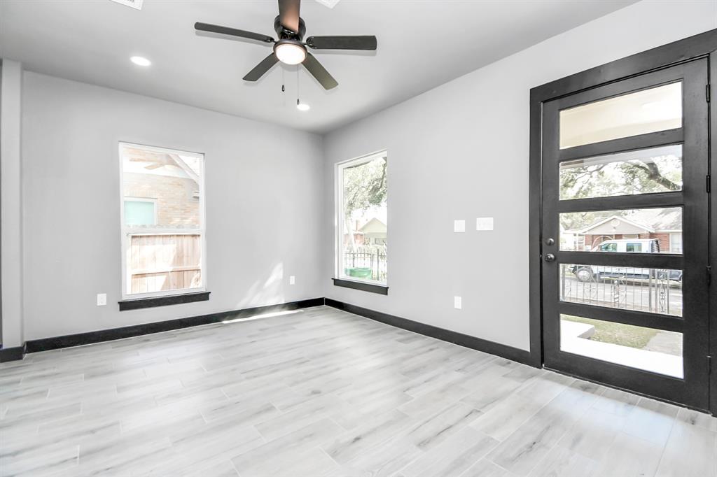 a view of an empty room with a window and wooden floor