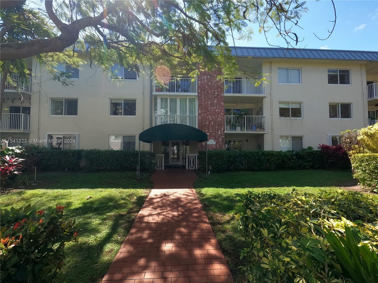 a front view of a house with a garden and trees