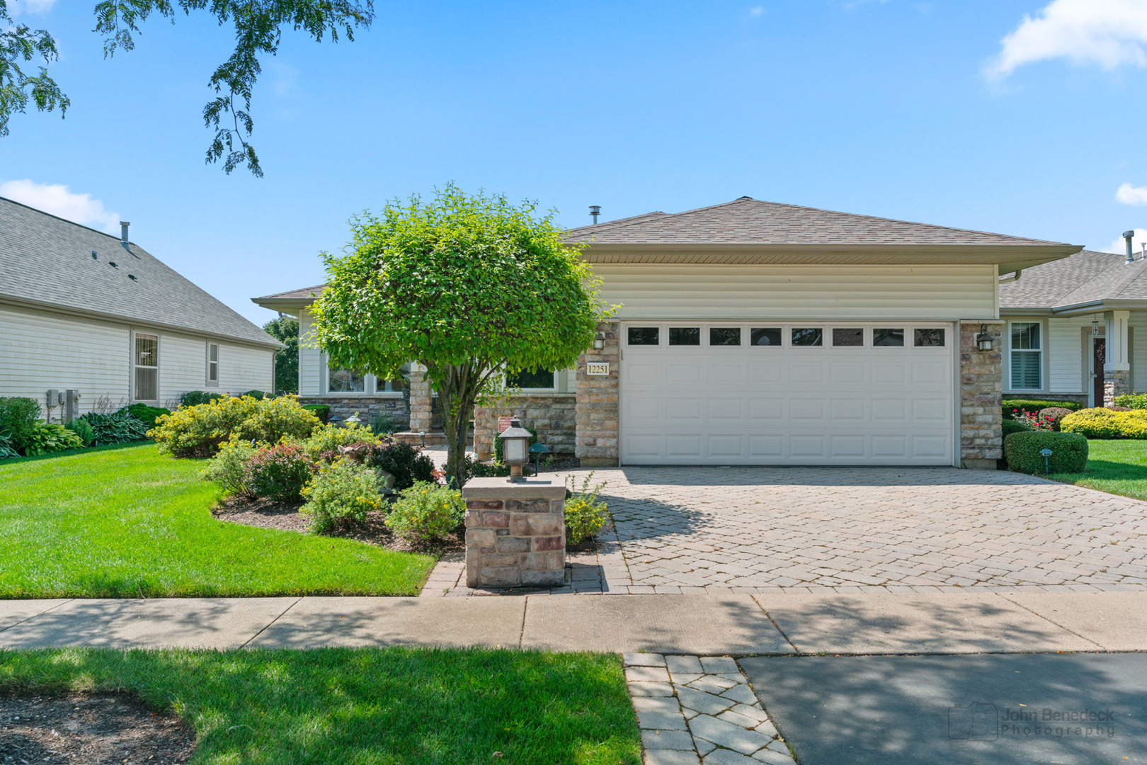 a front view of a house with a garden and a tree