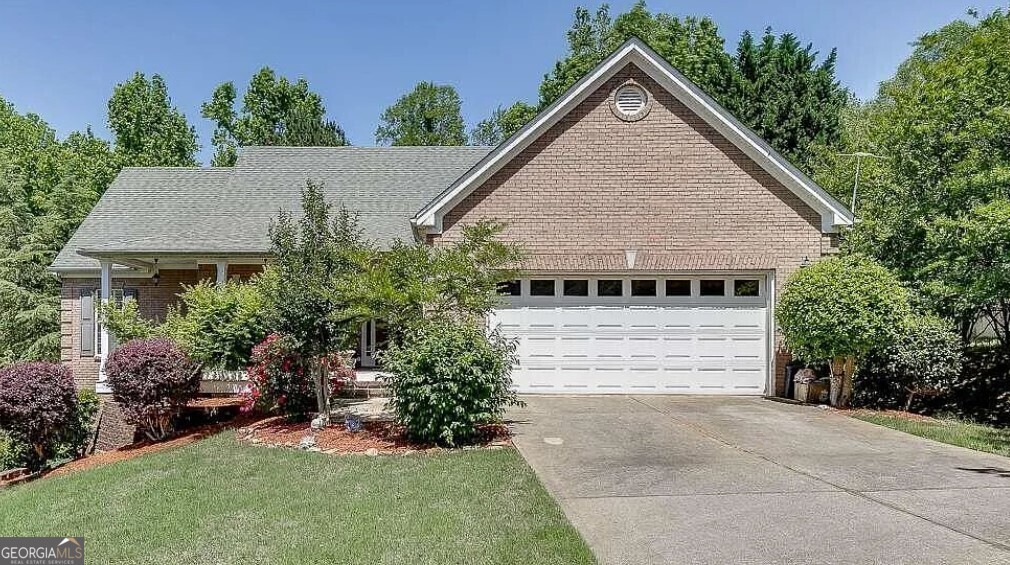 a view of a house with a yard plants and large tree