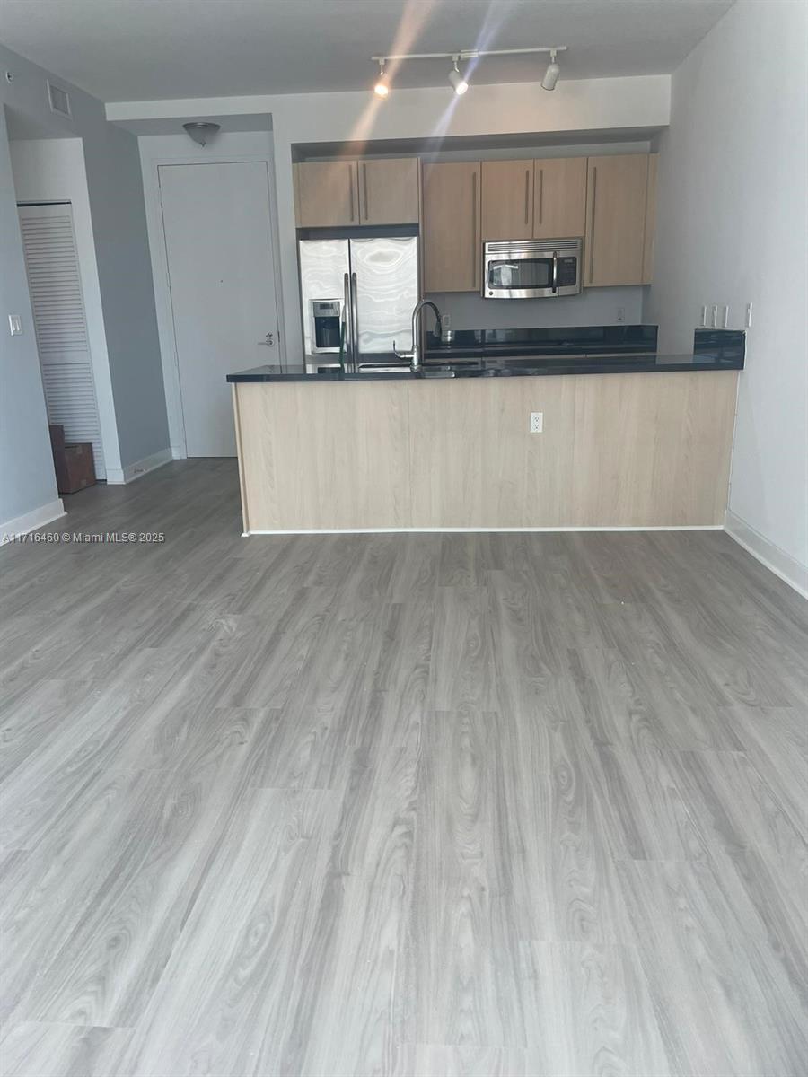 a view of a kitchen with wooden floor and electronic appliances