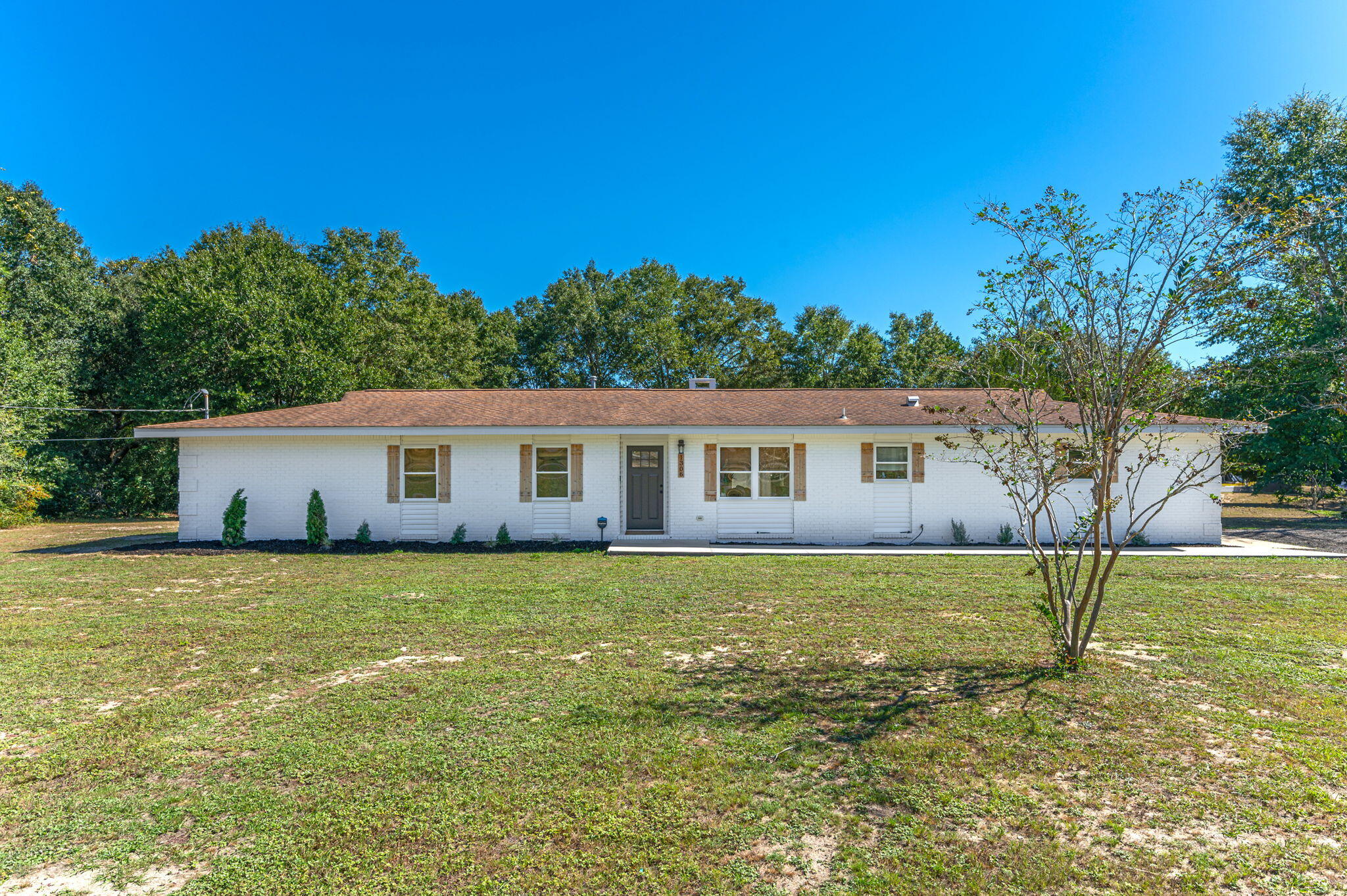 a house that is sitting in the grass with large trees