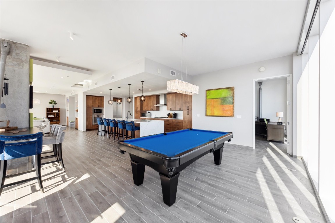 a room with furniture pool table wooden floor and windows