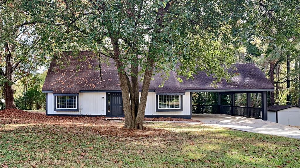 a view of a house with a yard and large tree