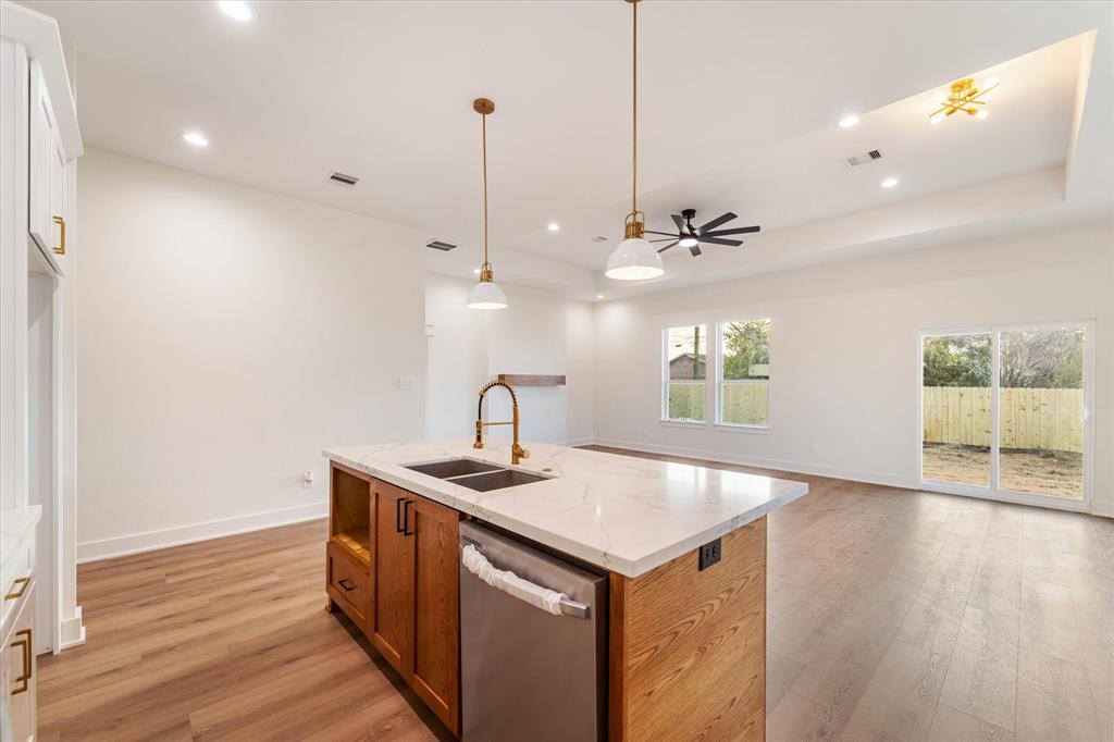 a kitchen with a sink chandelier and wooden floor