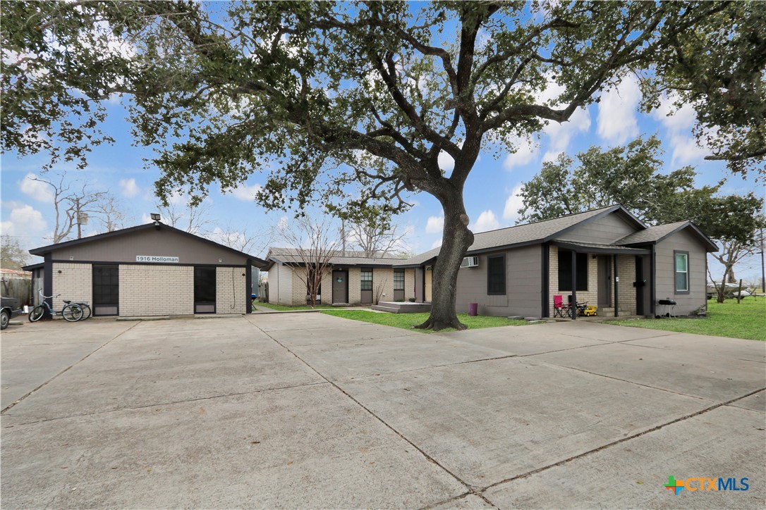 a front view of a house with a garden and trees