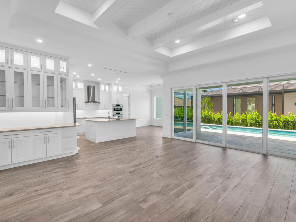 a view of an empty room with wooden floor and a kitchen