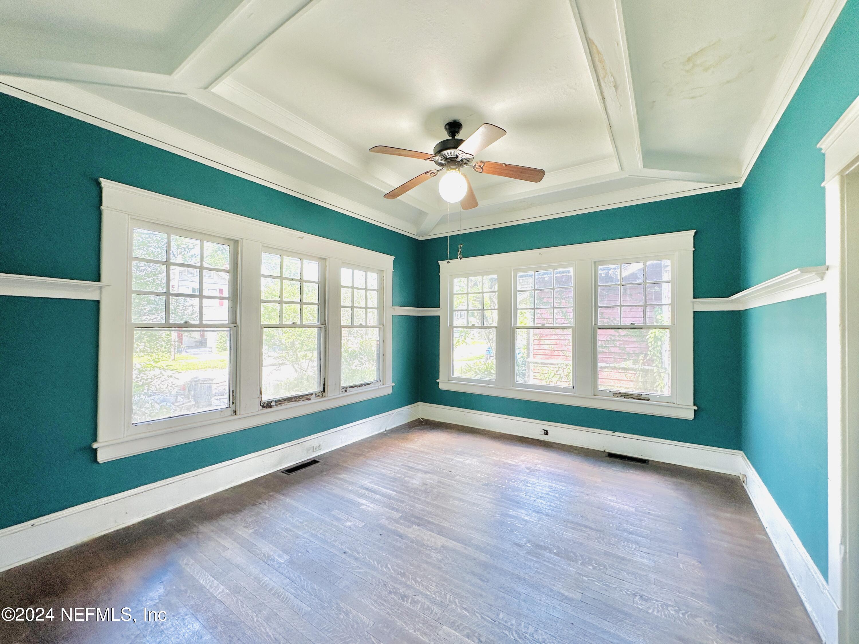 a view of empty room with wooden floor and fan