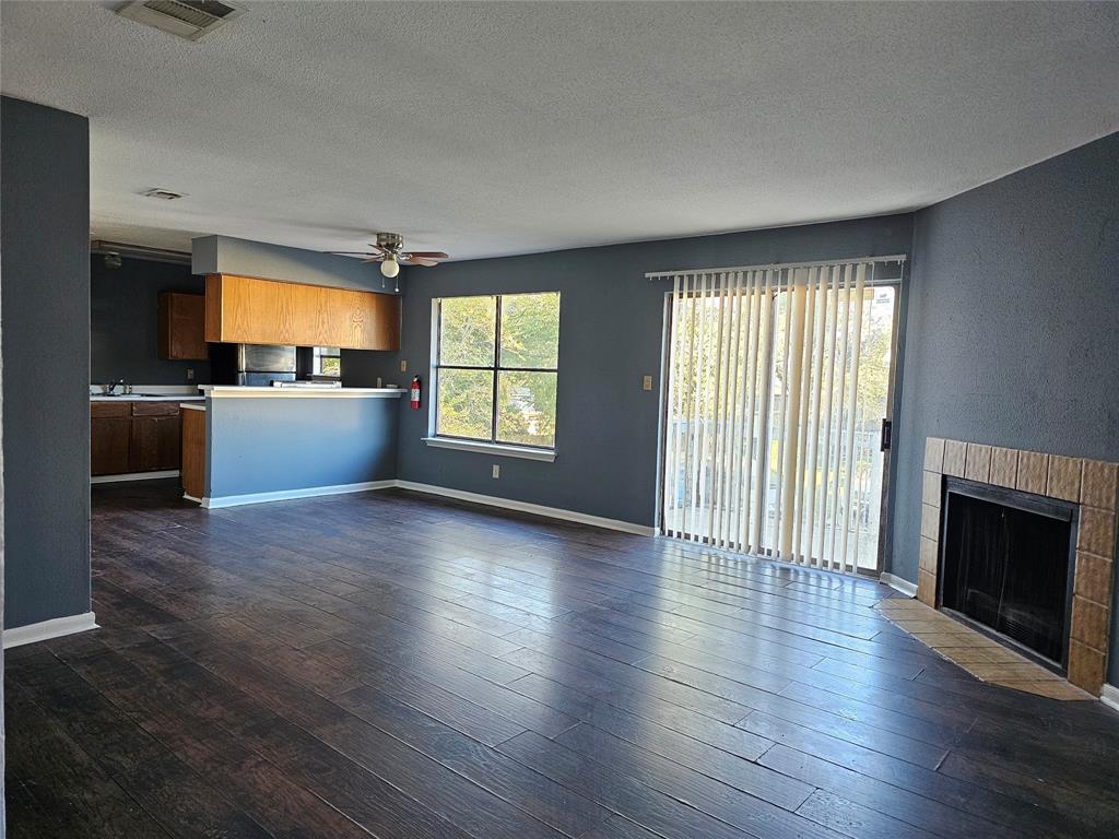 an empty room with wooden floor fireplace and windows