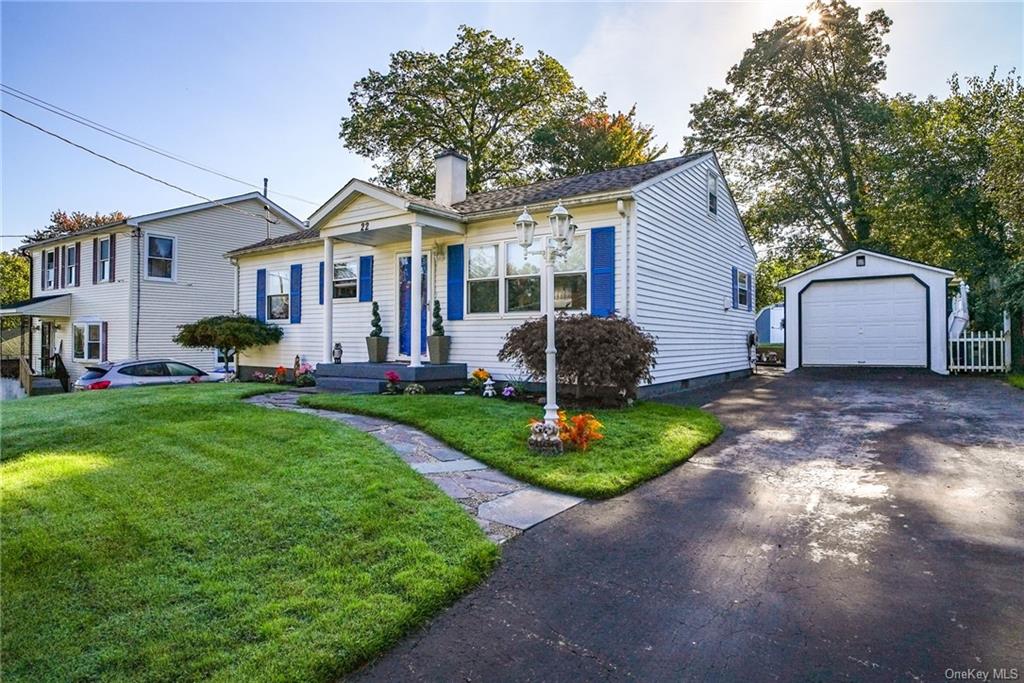 View of front facade with a garage, a front yard, and an outdoor structure