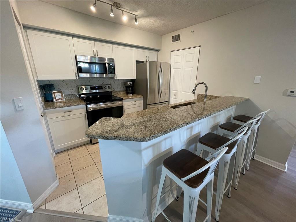 a kitchen with kitchen island granite countertop stainless steel appliances a sink and a refrigerator