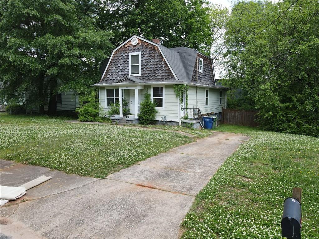 a front view of a house with a garden and trees