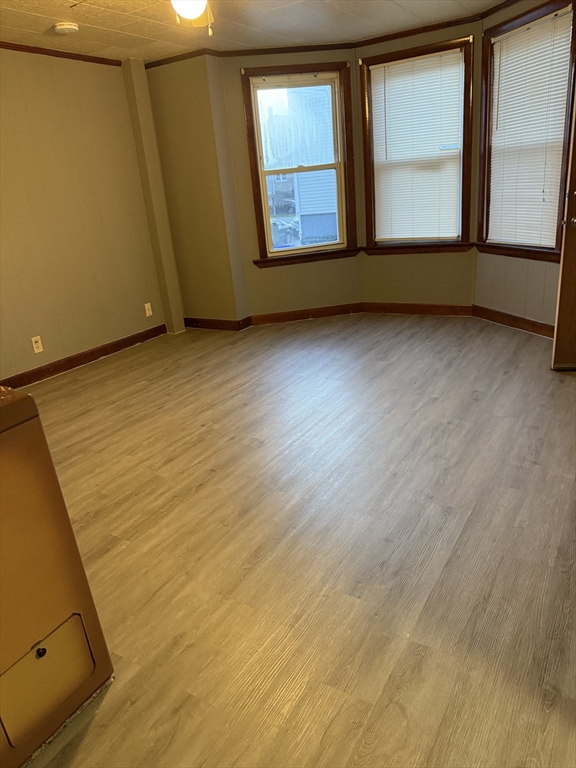 a view of an empty room with wooden floor and fan