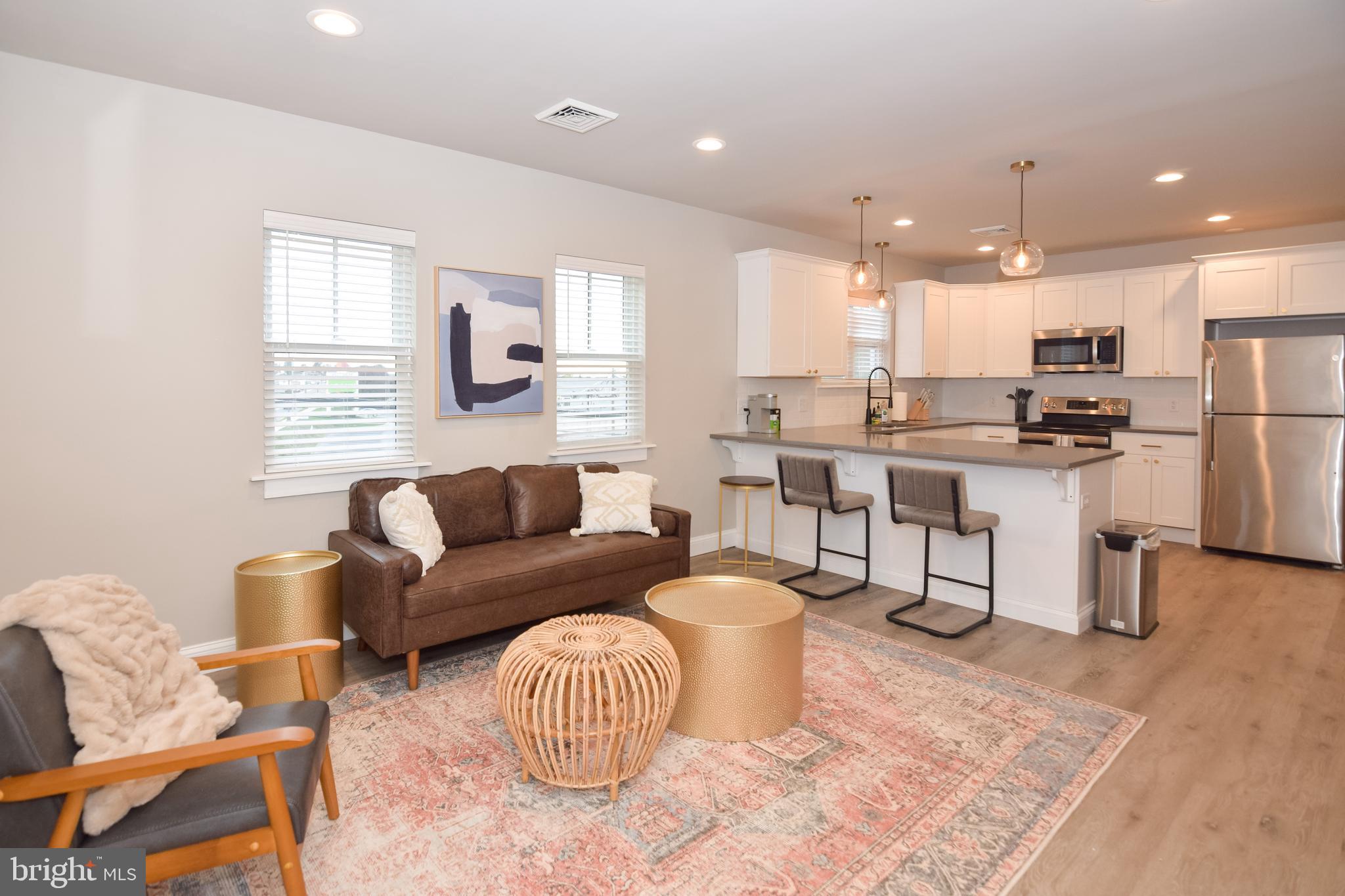 a living room with furniture a kitchen view and a window