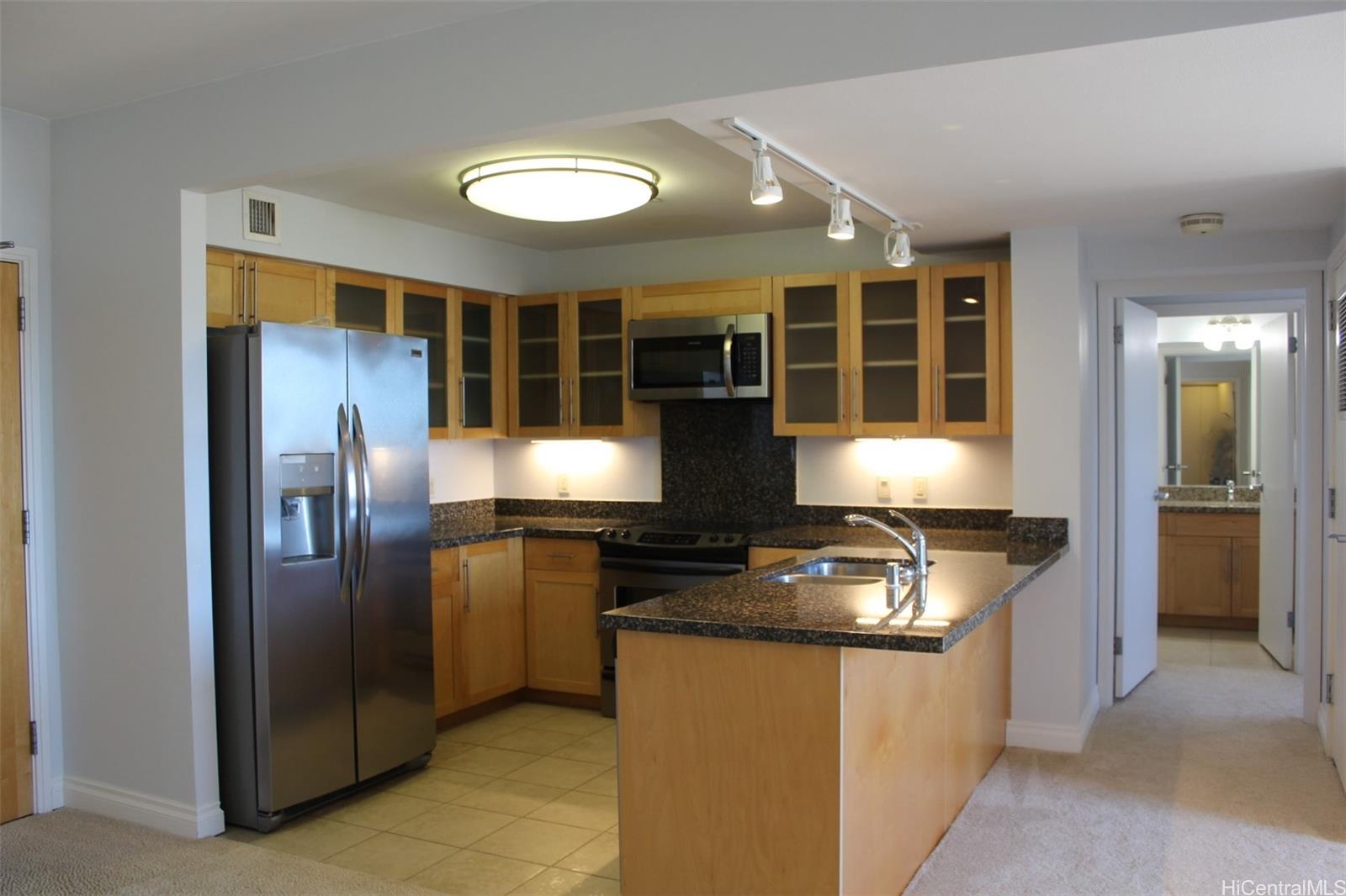 a kitchen with granite countertop stainless steel appliances a stove refrigerator and cabinets