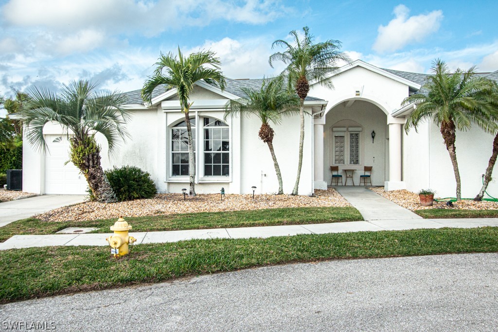 a view of a house with a yard and palm trees