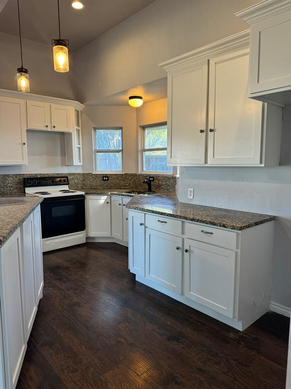 a kitchen with granite countertop white cabinets and a wooden floor