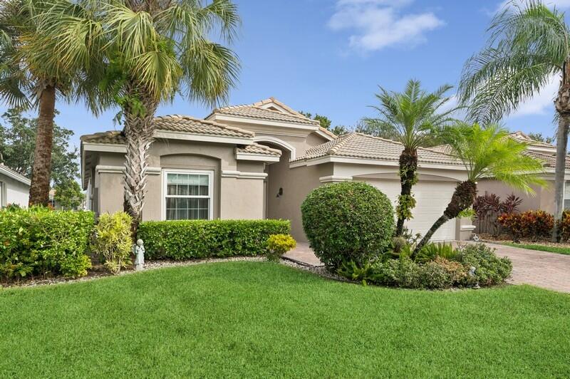 a view of a white house with a yard and palm trees