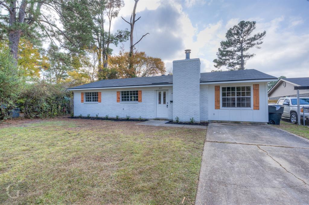 front view of house with a yard and trees