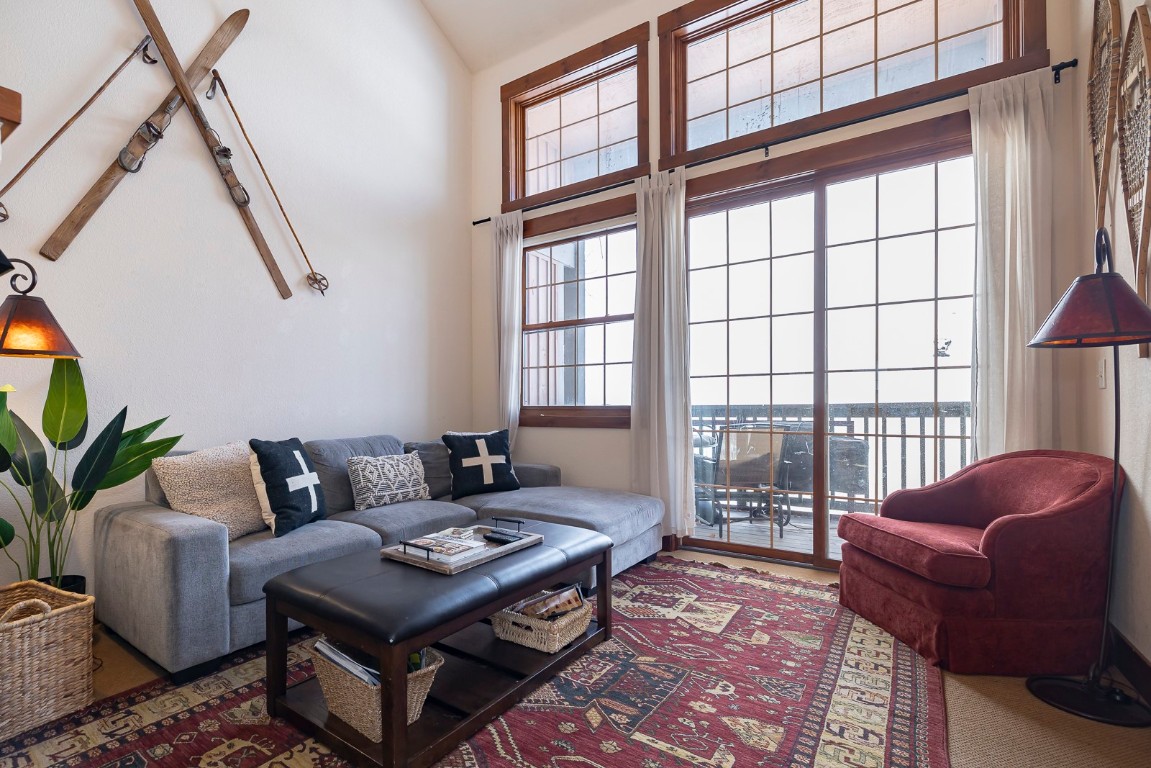 Carpeted living room featuring high vaulted ceiling