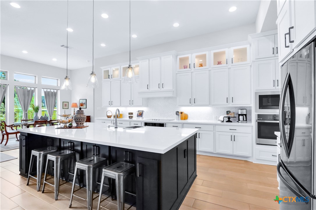 a kitchen with a sink a center island stainless steel appliances and cabinets