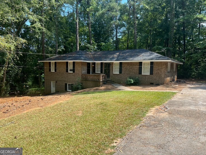 a front view of house with yard and trees in the background