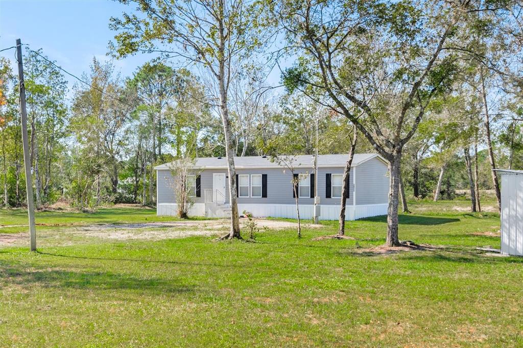 a white house with a big yard and large trees